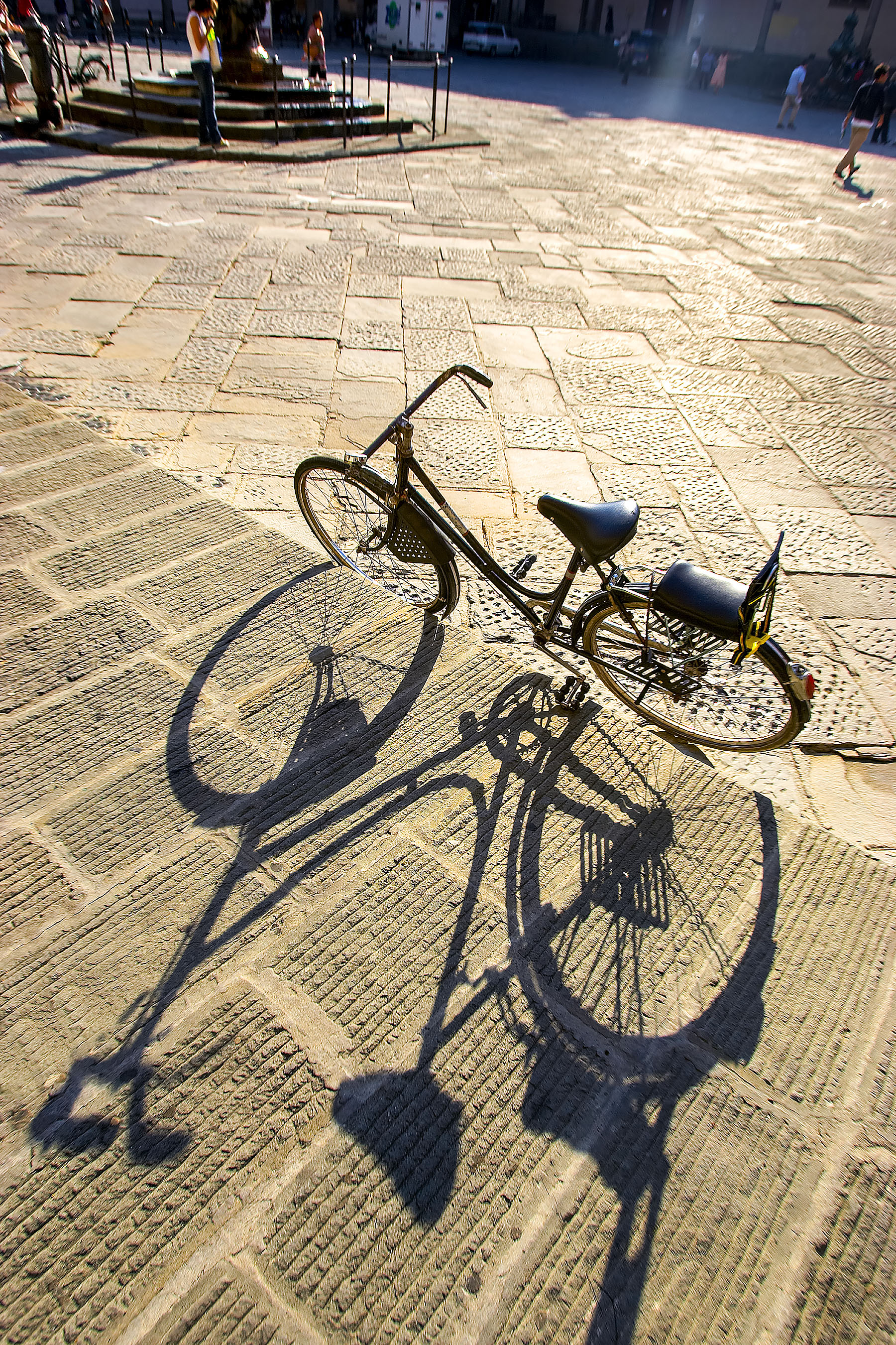 Bicycle in Plaza, piazza in Florence Italy with long shadow on cobblestone